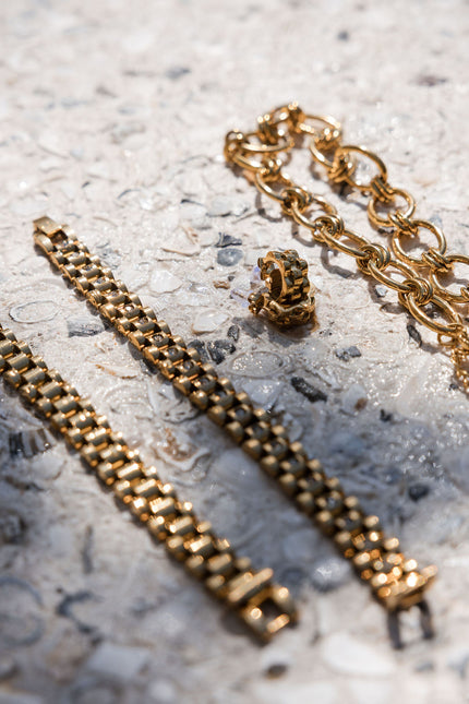 Gold chain bracelet and necklace on a textured surface
