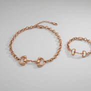 Gold horse bit necklace and matching bracelet on a white background