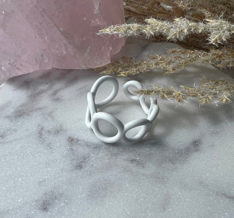 White colored enamel ring with small circle cut outs adjustable in size