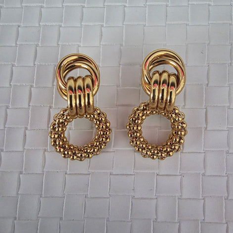 Pair of gold earrings on a textured white background