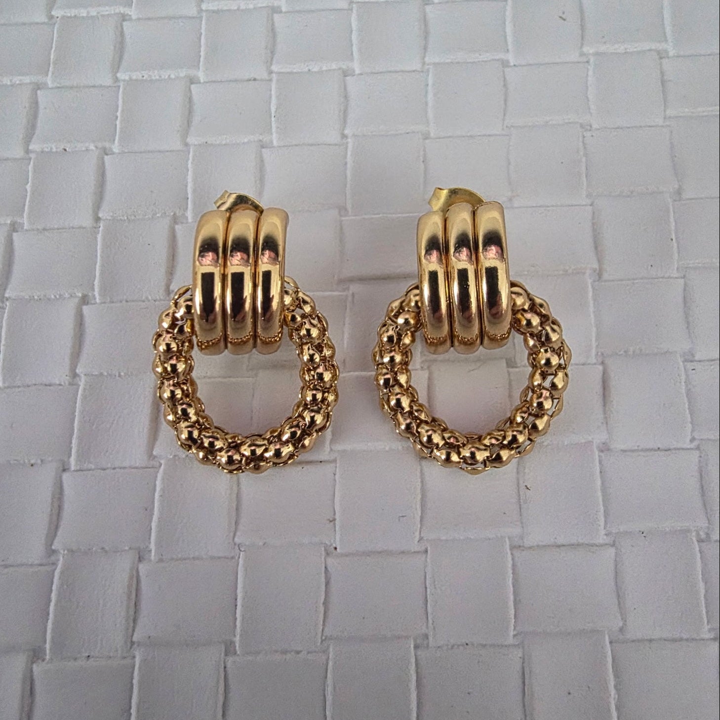 Gold hoop earrings on a textured surface