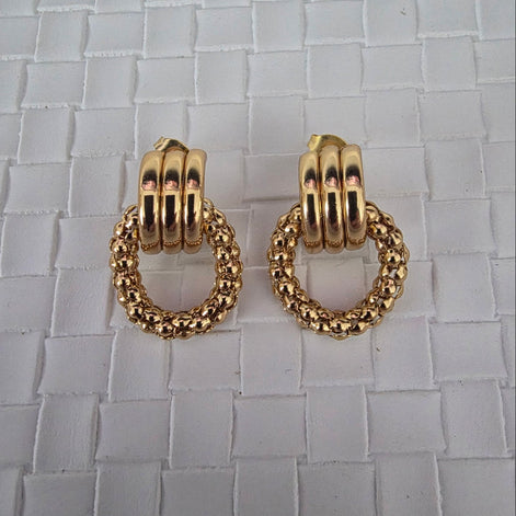 Gold hoop earrings on a textured surface