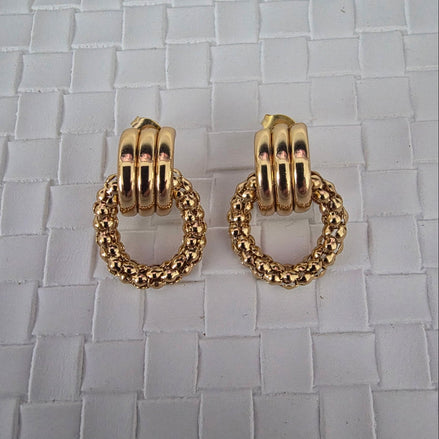 Gold hoop earrings on a textured surface