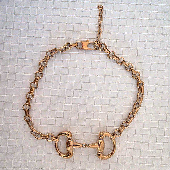Gold chain snaffle bit necklace on a white background