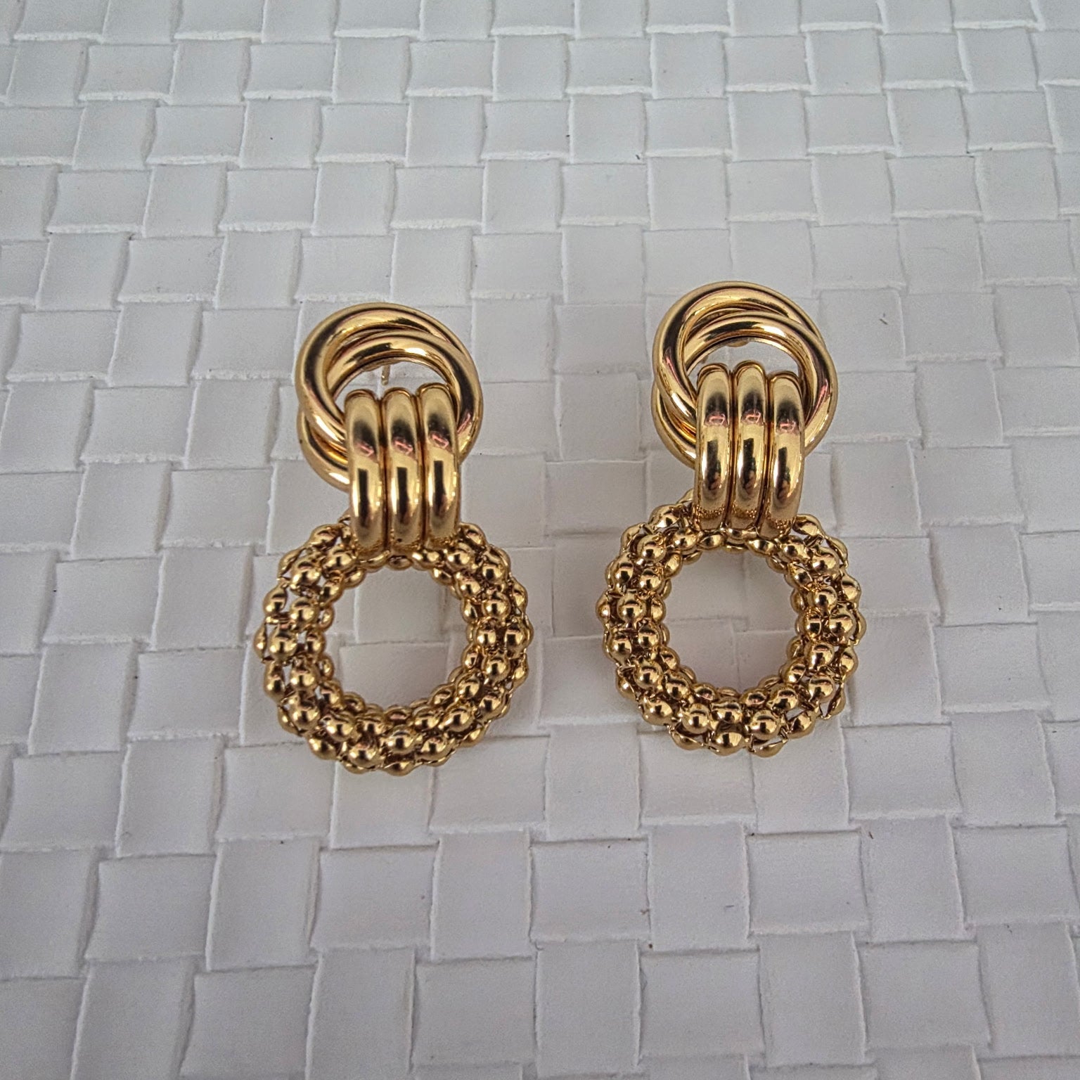 Pair of gold earrings on a textured white background