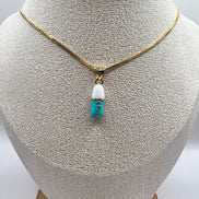 gold chain pendant holding a tiffany blue colored pill charm with the word chill written in gold letters on the pill charm