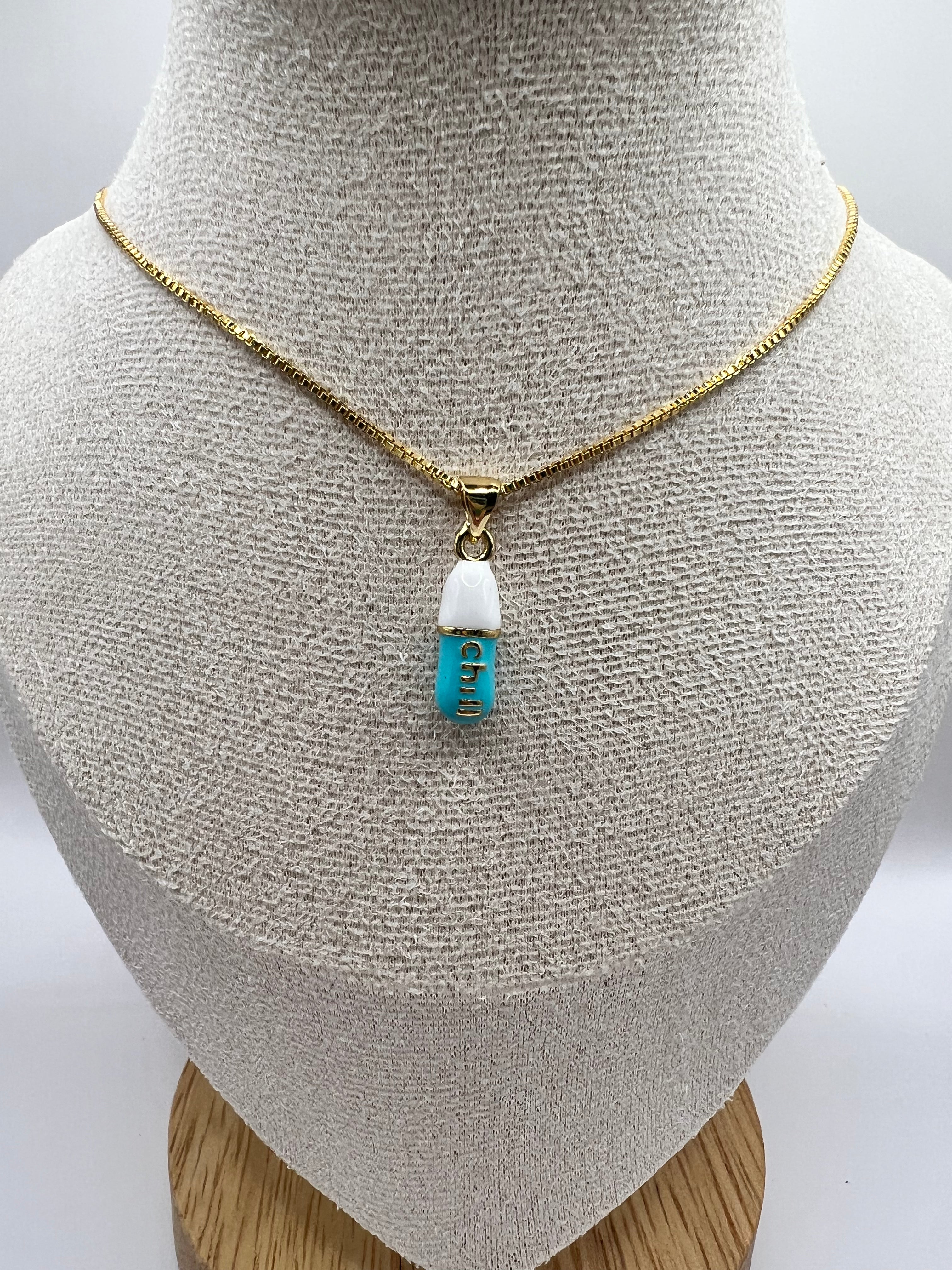 gold chain pendant holding a tiffany blue colored pill charm with the word chill written in gold letters on the pill charm