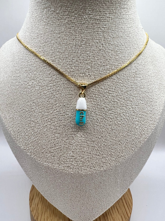 gold chain pendant holding a tiffany blue colored pill charm with the word chill written in gold letters on the pill charm