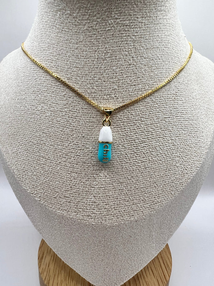 gold chain pendant holding a tiffany blue colored pill charm with the word chill written in gold letters on the pill charm