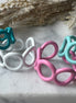 Teal, white, pink and mint green blue colored enamel rings with small circle cut outs adjustable in size