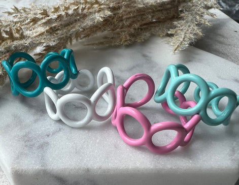 Teal, white, pink and mint green blue colored enamel rings with small circle cut outs adjustable in size