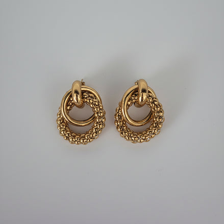 Pair of gold hoop earrings on a light gray background