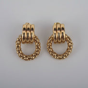 Pair of gold hoop earrings on a textured white background