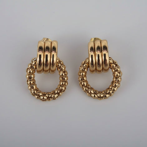 Pair of gold hoop earrings on a textured white background