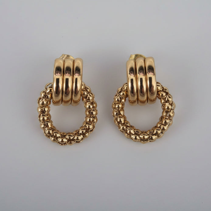 Pair of gold hoop earrings on a textured white background