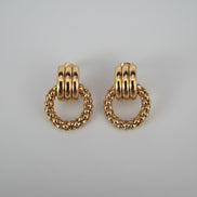 Gold hoop earrings on a textured surface