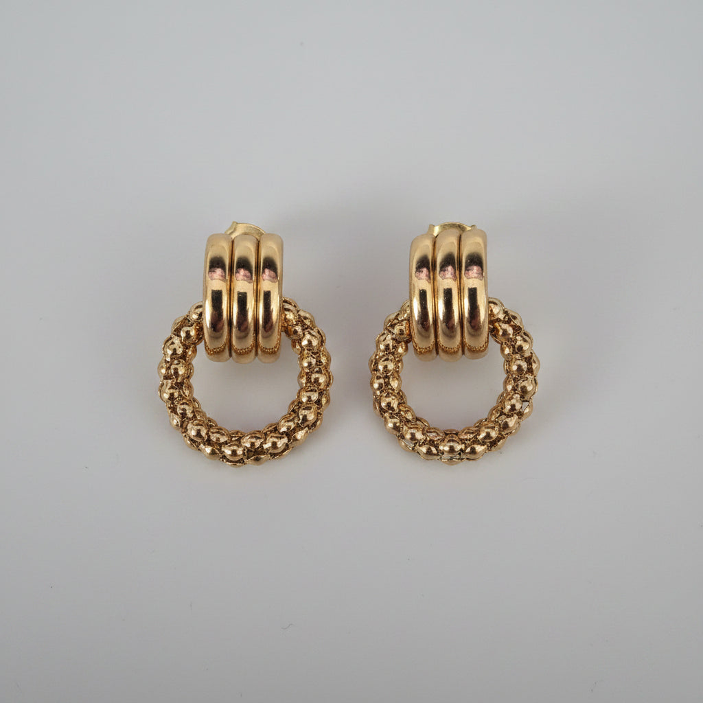 Gold hoop earrings on a textured surface