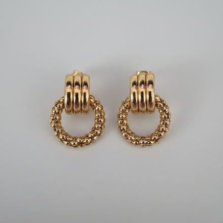 Gold hoop earrings on a textured surface