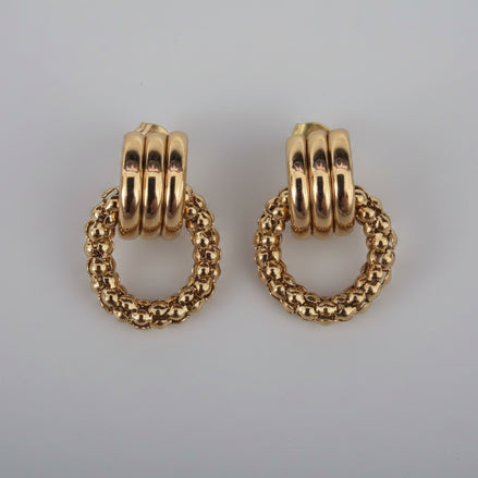 Pair of gold hoop earrings on a textured white background