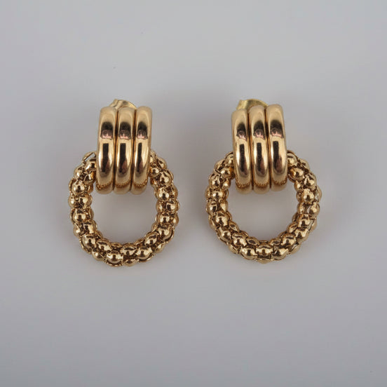 Pair of gold hoop earrings on a textured white background