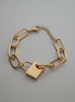 Gold chain bracelet with a padlock charm on a white background