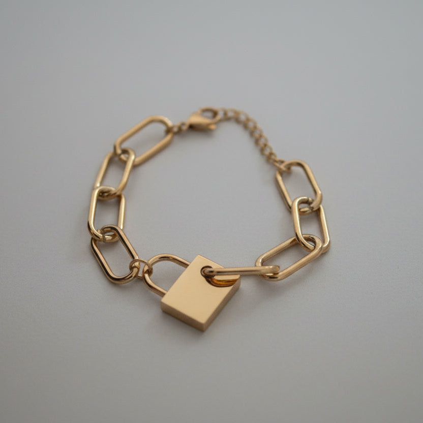 Gold chain bracelet with a padlock charm on a white background