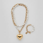 Necklace and bracelet set with heart pendant on a textured surface