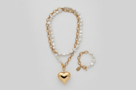 Necklace and bracelet set with heart pendant on a textured surface