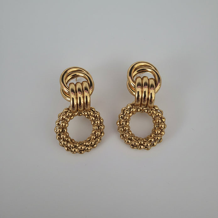 Pair of gold earrings on a textured white background