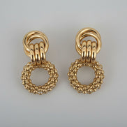 Pair of gold earrings on a textured white background