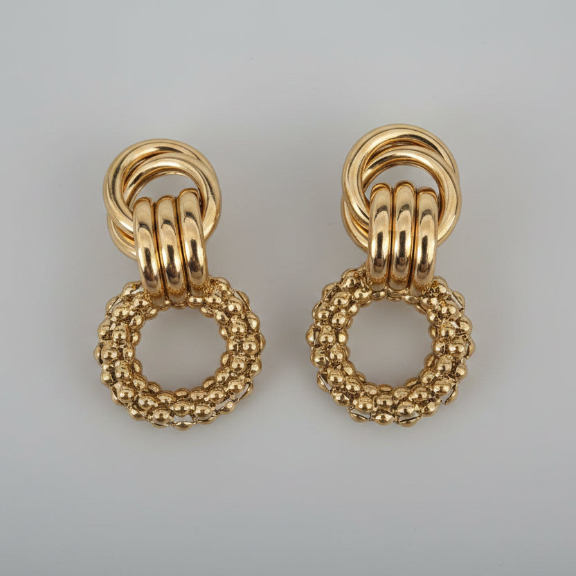 Pair of gold earrings on a textured white background