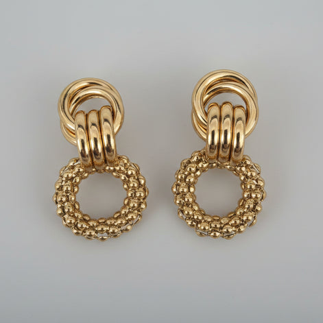 Pair of gold earrings on a textured white background