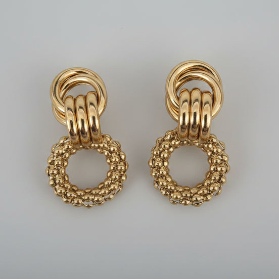 Pair of gold earrings on a textured white background