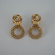 Pair of gold hoop earrings on a textured white background