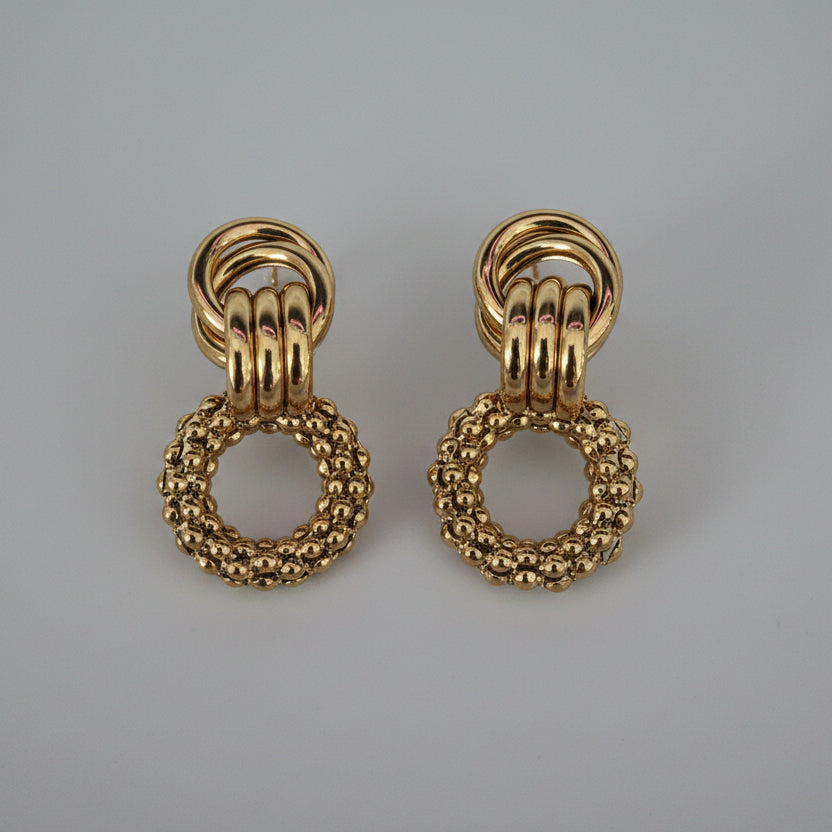 Pair of gold hoop earrings on a textured white background