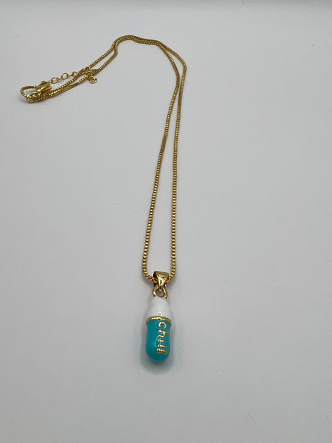 gold chain pendant holding a tiffany blue colored pill charm with the word chill written in gold letters on the pill charm