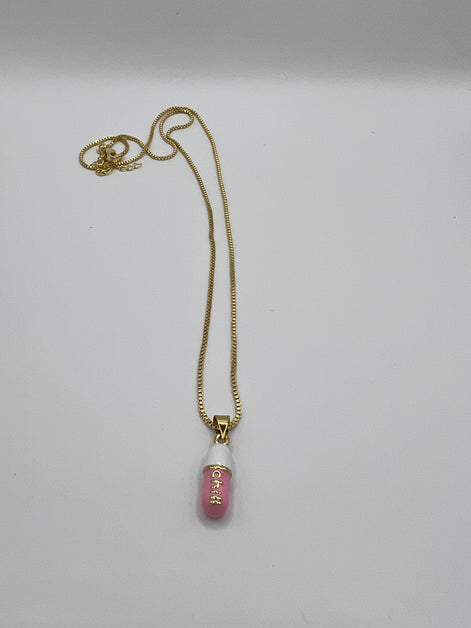 gold chain pendant holding a pink colored pill charm with the word chill written in gold letters on the pill charm