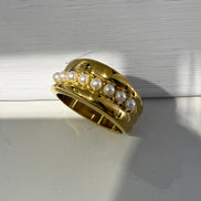 Gold ring with pearls on a neutral background