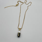 gold chain pendant holding a black colored pill charm with the word chill written in gold letters on the pill charm