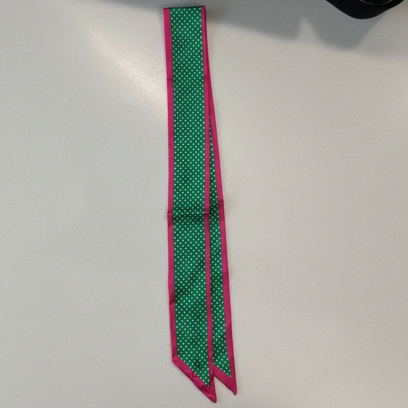 Green scarf with white polka dots and a pink border on a white background