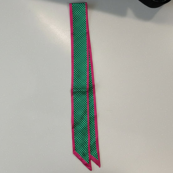 Green scarf with white polka dots and a pink border on a white background