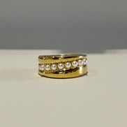Gold ring with embedded pearls on a neutral background