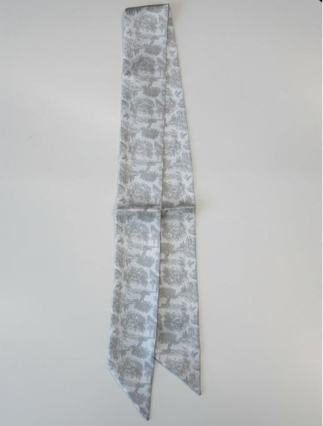 Greige toile floral-patterned silk scarf on a white surface