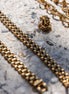 Gold chain bracelet and earrings on a textured surface