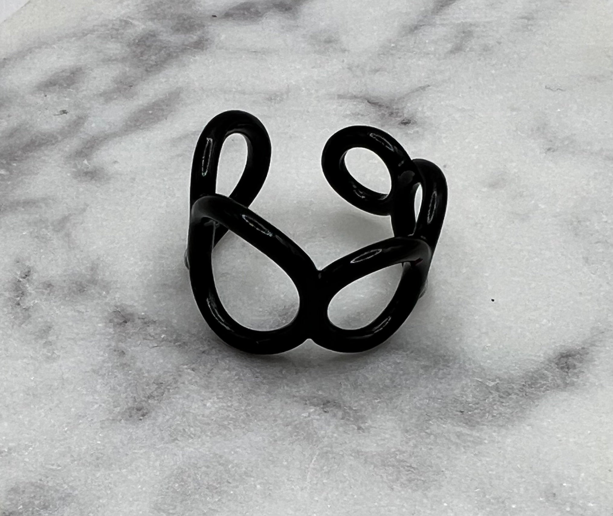 Black colored enamel ring with small circle cut outs adjustable in size