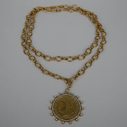 Gold chain necklace with a pendant on a textured white surface