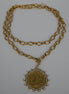 Gold chain necklace with a pendant on a textured white surface