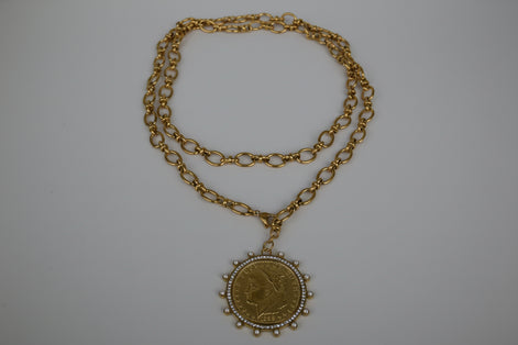 Gold chain necklace with a pendant on a textured white surface