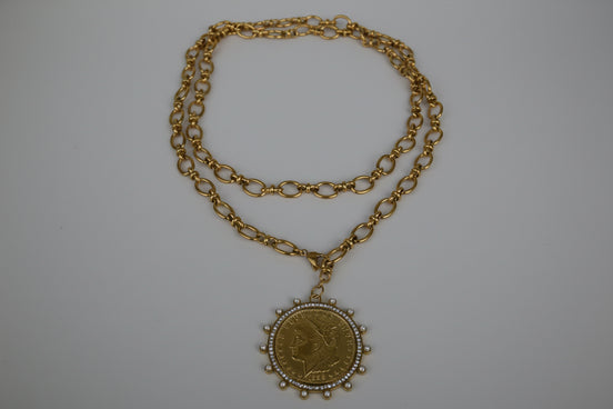 Gold chain necklace with a pendant on a textured white surface