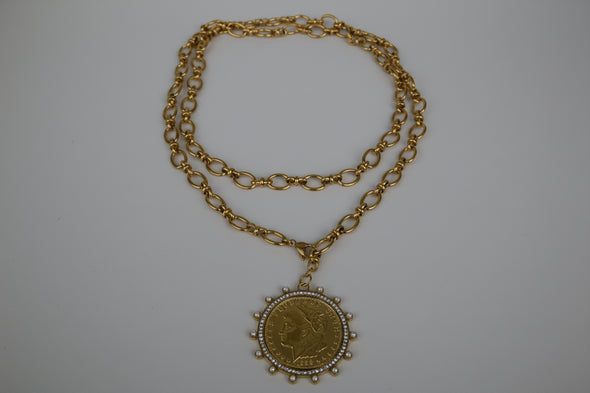 Gold chain necklace with a pendant on a textured white surface